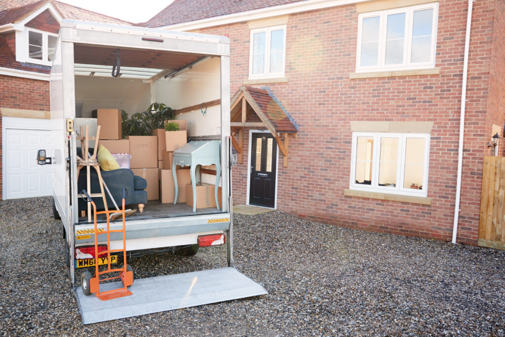 Removal van loaded with boxes and household furniture outside a home during a house move.