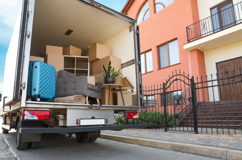 Removal van loaded with boxes, furniture and luggage outside a residential property.
